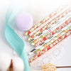 A collection of colorful striped and polka dot paper drinking straws with floral accents and a pale yellow flower