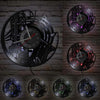 A collection of vintage vinyl record wall clocks featuring intricate designs and glowing accents mounted on a gray brick wall