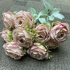 A bouquet of nine realistic silk roses in soft blush pink and cream tones with green foliage.