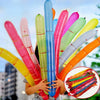 A child holds a colorful rocket balloon strip party decoration featuring pink, green, and blue balloons.
