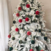 A decorated Christmas tree featuring a variety of red, white, and green velvet baubles and ornaments.