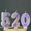 Five fifty number candles in purple sparkling glitter on a wooden surface
