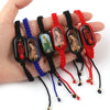 A hand holds several vintage wooden Virgin Mary prayer bracelets in various colors like black, blue, green, and red.
