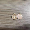 A pair of gold-colored St. Benedict religious pendants or medals resting on a wooden surface.