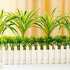 Artificial chlorophytum branches planted in a white planter for home decor