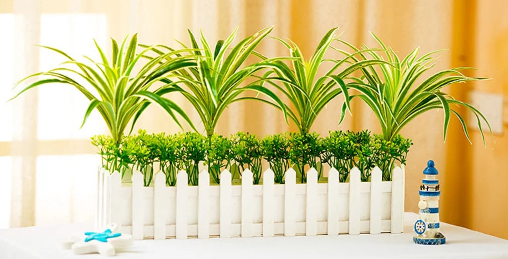 Artificial chlorophytum branches planted in a white planter for home decor
