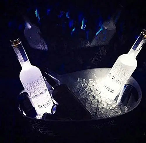 A close-up shot of two bottles illuminated by blue LED lights, resting on ice in a dark setting.