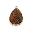 A teardrop-shaped natural agate pendant with a gold-colored bail, featuring brown and black swirling patterns.