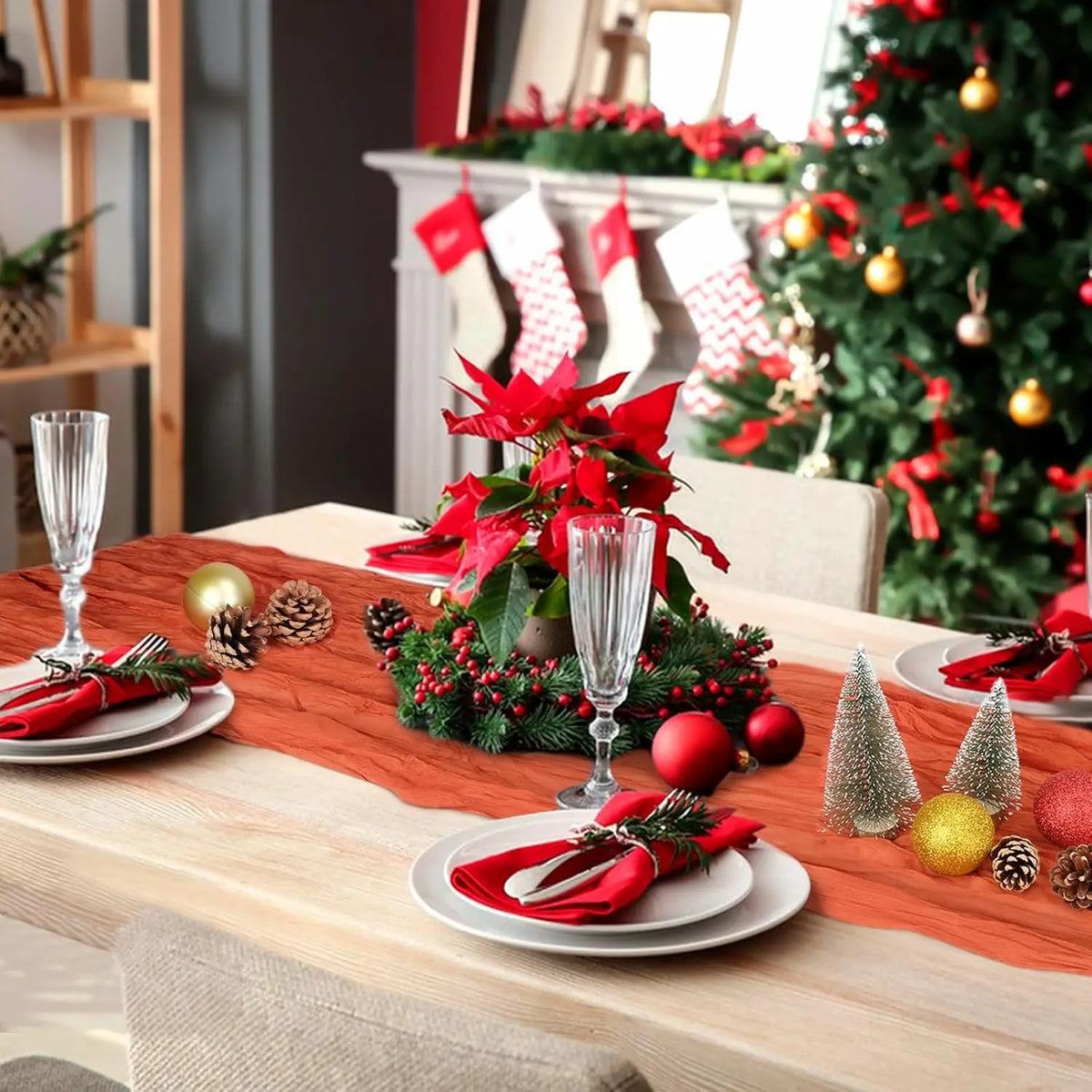 A terracotta semi-sheer cheesecloth table runner set with red accents and festive holiday decorations on a wooden table.