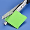 Stainless steel pinking scissors with a zig zag blade cutting a green piece of paper