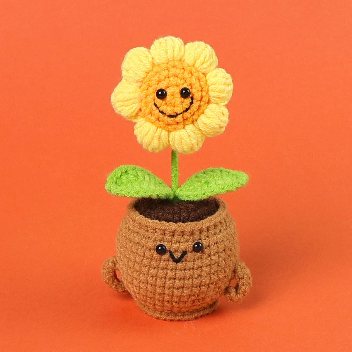 Handmade crochet sunflower desk companion with a smiling face, featuring yellow petals and green leaves.