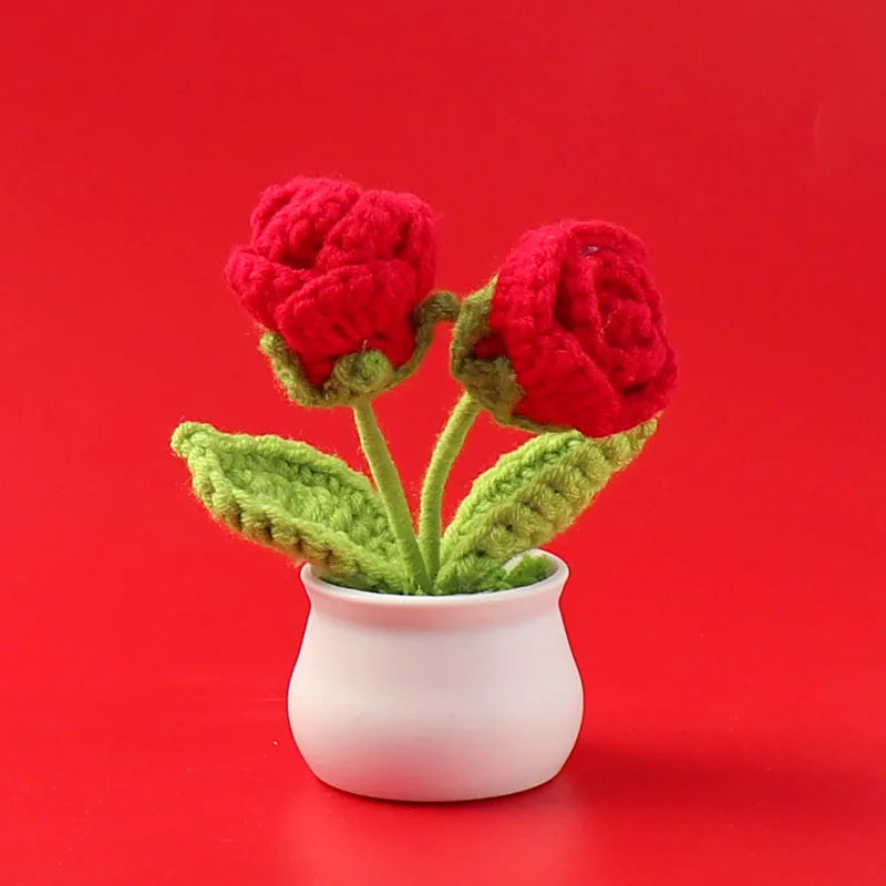 Hand woven crochet red roses potted in a white ceramic cup against a red background
