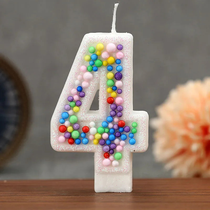 A white candle shaped like the number 4 decorated with colorful candy beads for a birthday celebration.