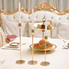 A set of three gold-toned metal taper candle holders with white candles displayed on a white table.