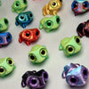 A collection of 3D printed frog car ornaments featuring various colors and color-shifting eyes.