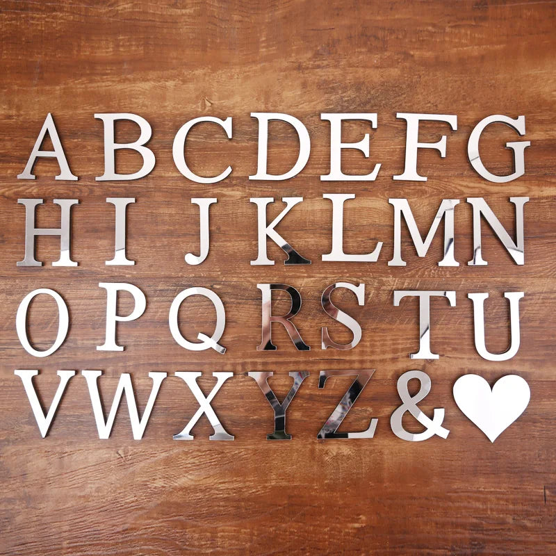 A display of gold acrylic mirror letter wall stickers spelling out the alphabet and symbols on a wooden surface.