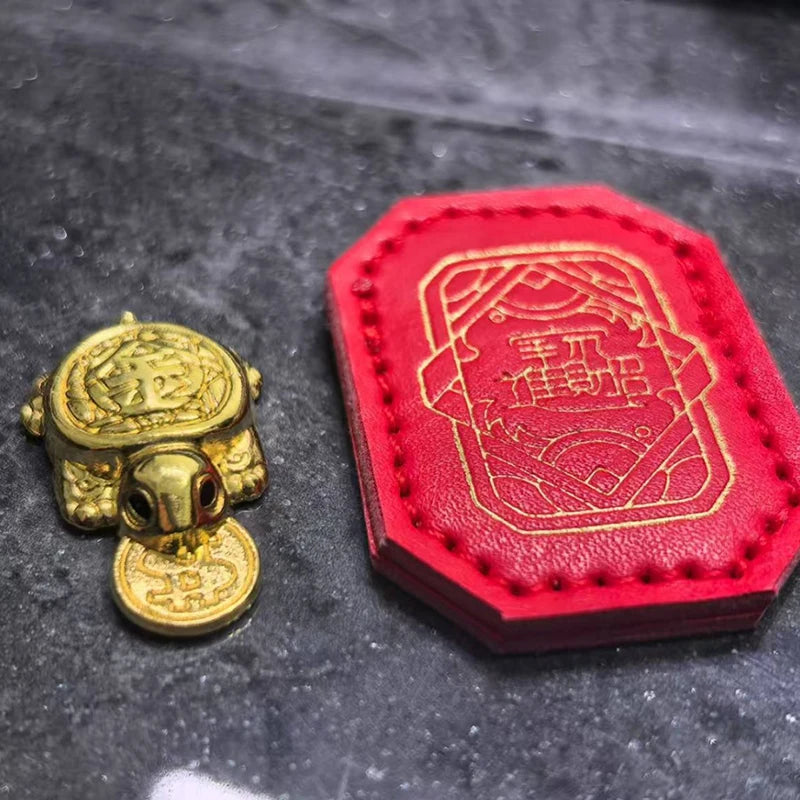 A golden tortoise figurine is displayed next to a red leather pouch embossed with Chinese characters.