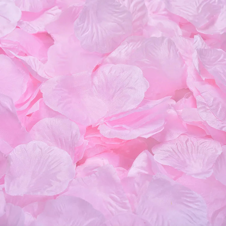 A close-up of pink artificial silk rose petals scattered on a surface.