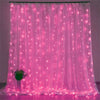 Pink sheer curtain illuminated by numerous glowing LED string lights