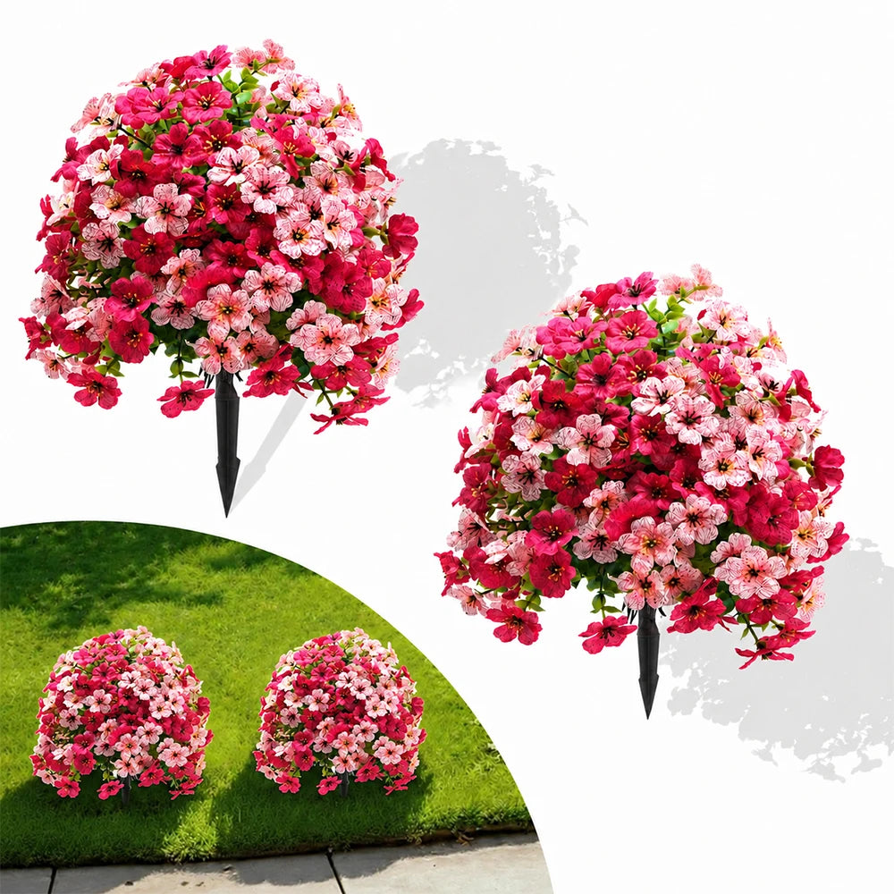 A vibrant display of artificial pink and red flowers shaped into topiary balls, shown in full bloom and planted in a green la