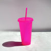 A bright pink glitter party cup with a pink lid and straw standing on a white surface.