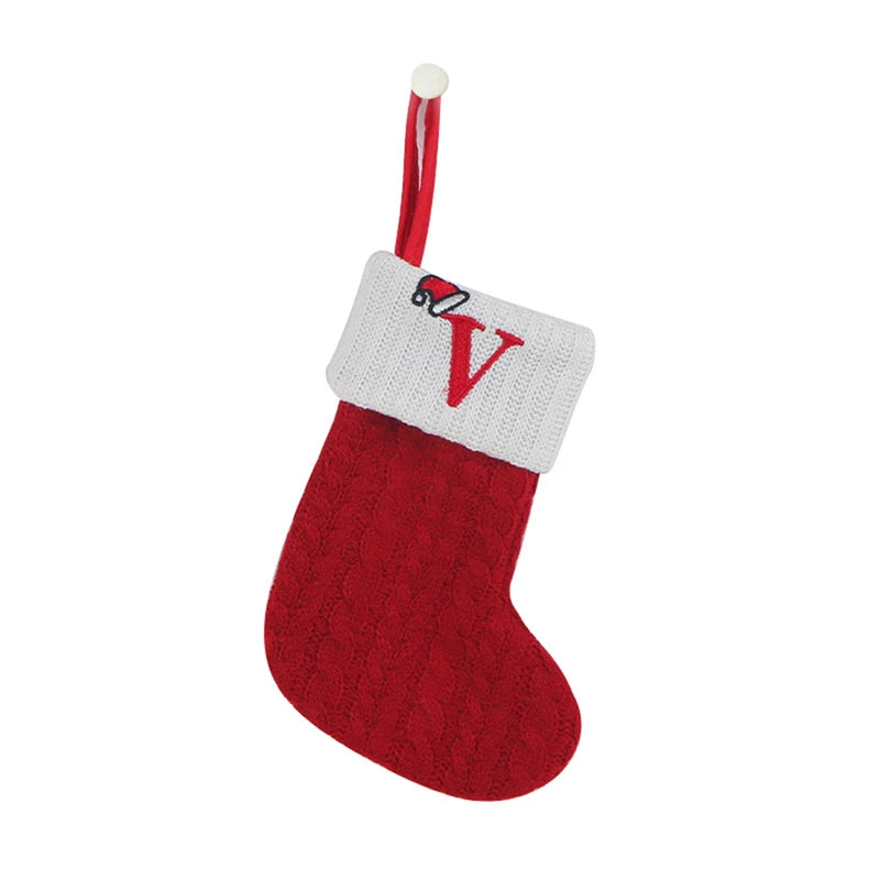 A red knitted sock with a white cuff and a red letter V decoration, hanging from a red ribbon.