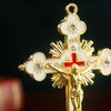 A gold-colored metal Jesus cross ornament featuring a figure of Christ and decorative elements.