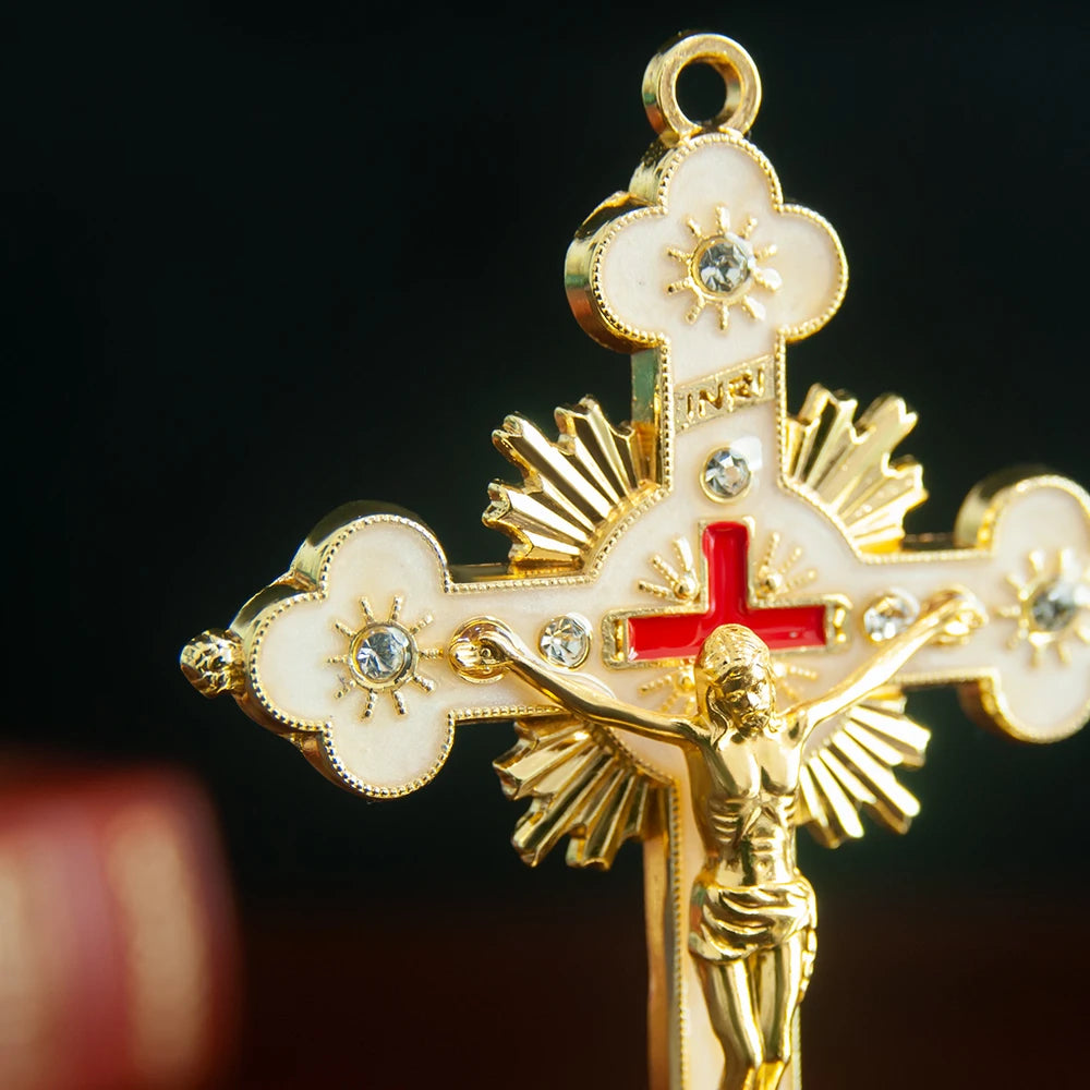 A gold-colored metal Jesus cross ornament featuring a figure of Christ and decorative elements.