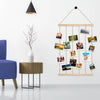 Collage photo rustique en bois avec des photos encadrées suspendues à de fins fils sur un mur blanc.