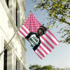 A person holds a pink and white striped flag with stars and text in front of a white building.