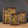 Three antique resin photo frames with distressed gold and dark green foliage designs displayed on a wooden surface.