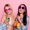 Two women smiling while holding glow-in-the-dark silicone bracelets and colorful drinks.