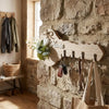Rustic wooden key holder with a heart accent and four hooks mounted on a stone wall.