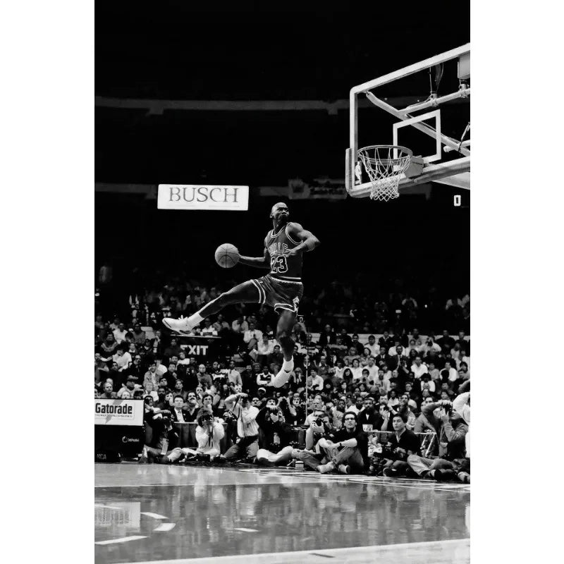 A black and white photo of a basketball player during a game, focusing on the action under a hoop.