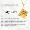 A gold pendant necklace shaped like an open book with German text engraved on it.