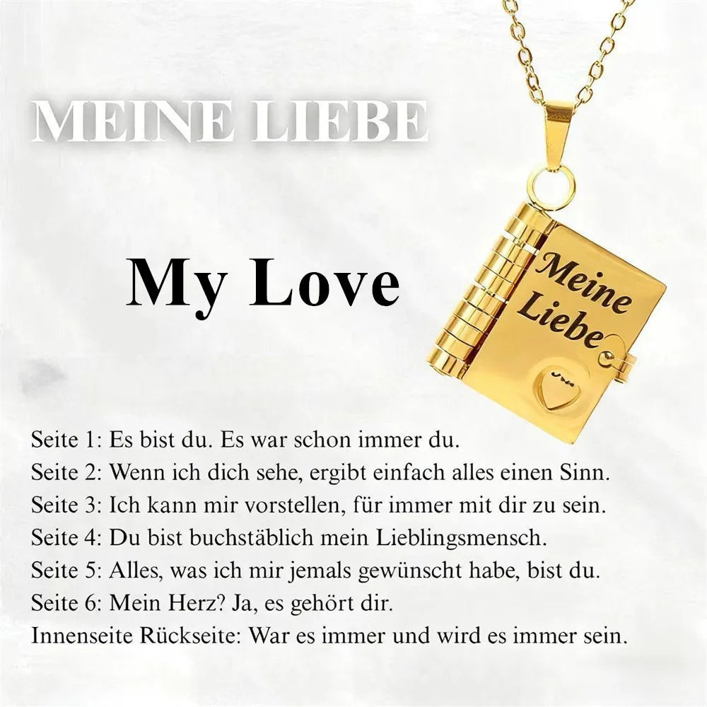 A gold pendant necklace shaped like an open book with German text engraved on it.