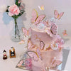 A tiered pink cake decorated with gold and pink butterfly toppers on a white background.