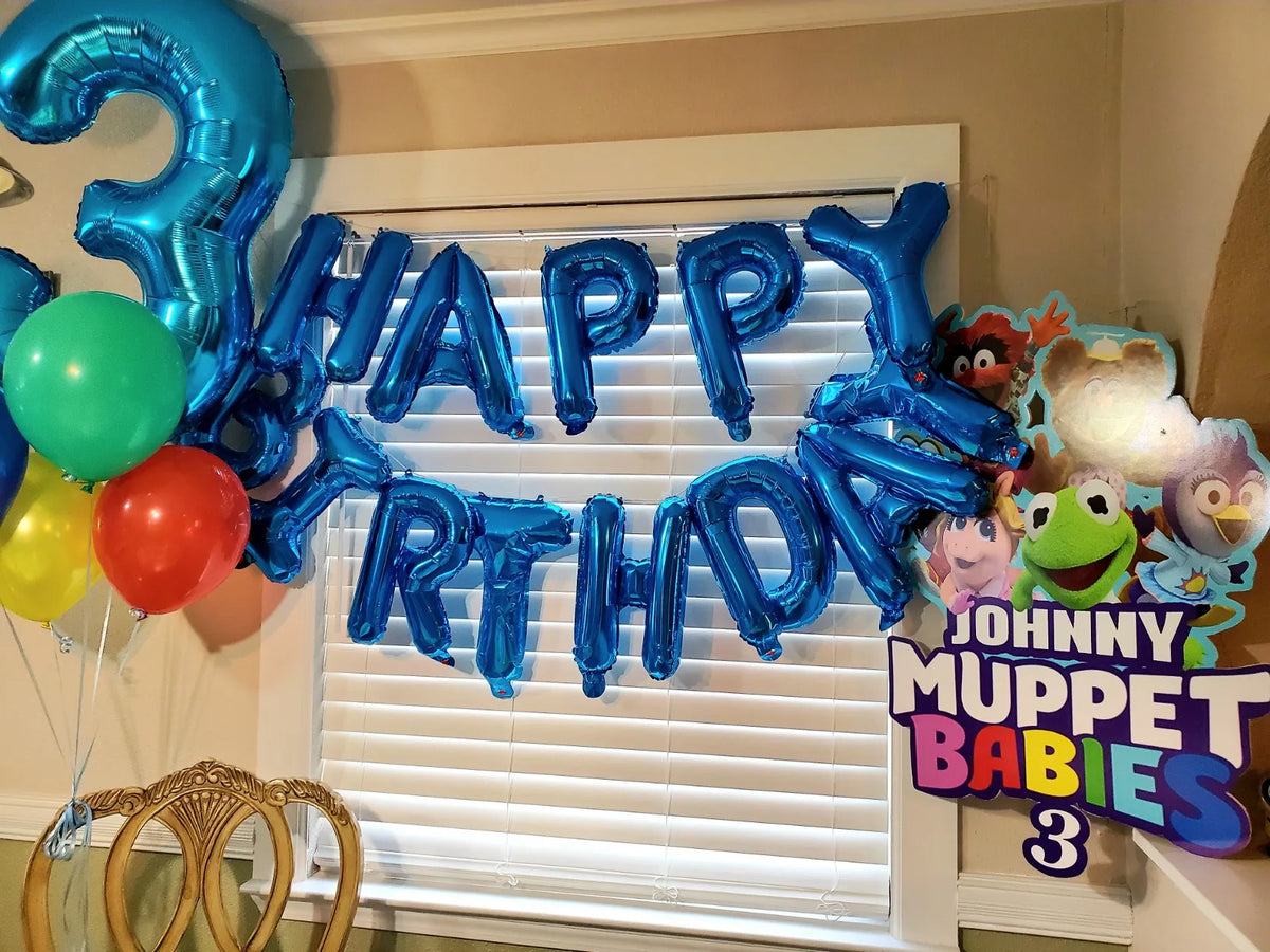 Blue foil letter balloons spelling HAPPY BIRTHDAY decorating a window for a birthday party