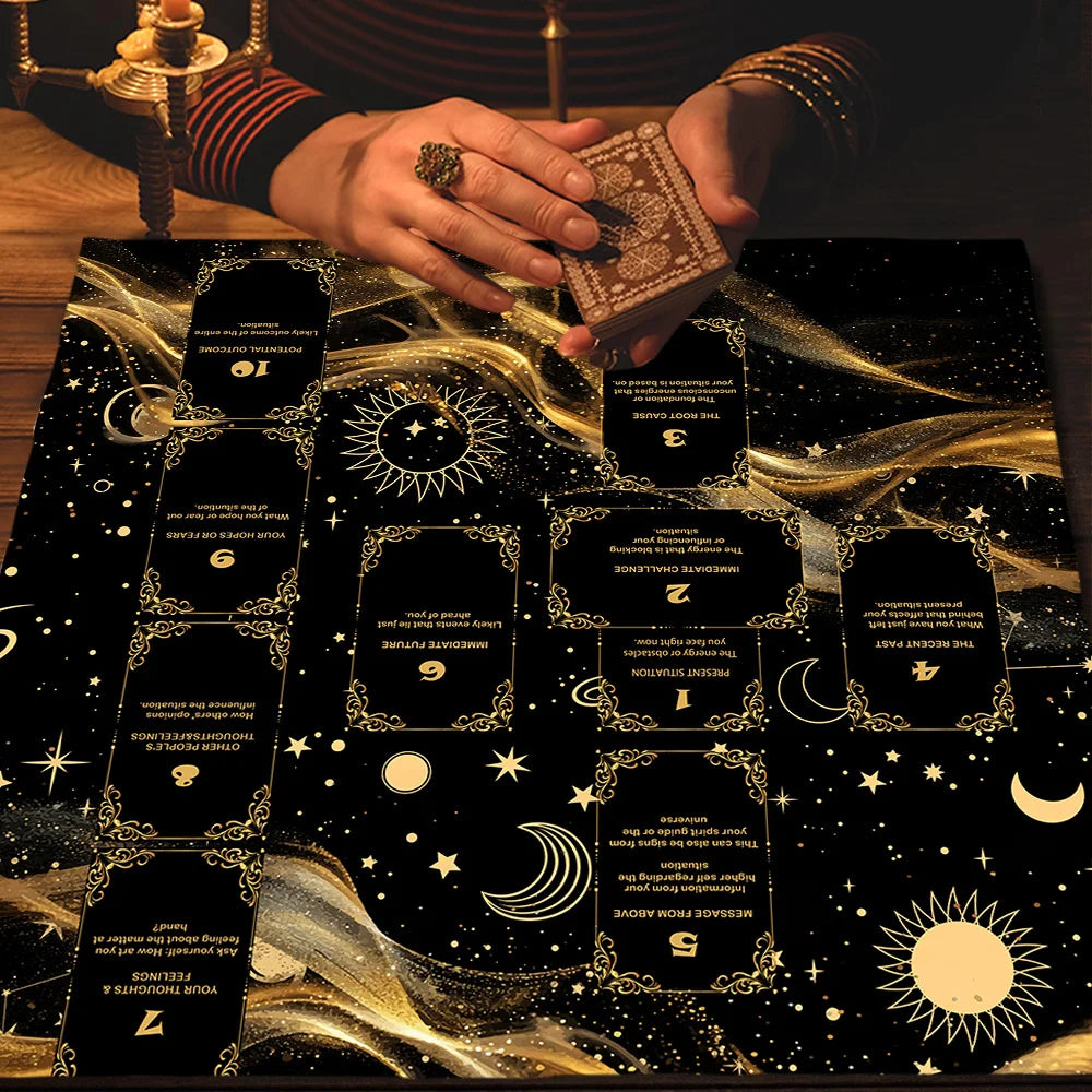 A hand places a tarot altar cloth with gold accents onto a dark surface.