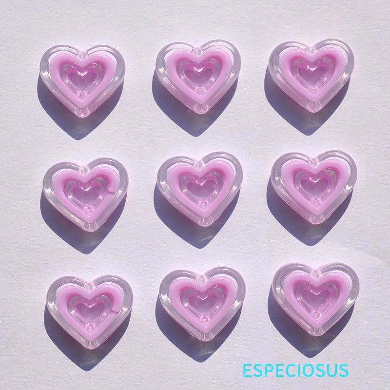 A set of six translucent pink heart-shaped acrylic charms casting shadows on a white surface.