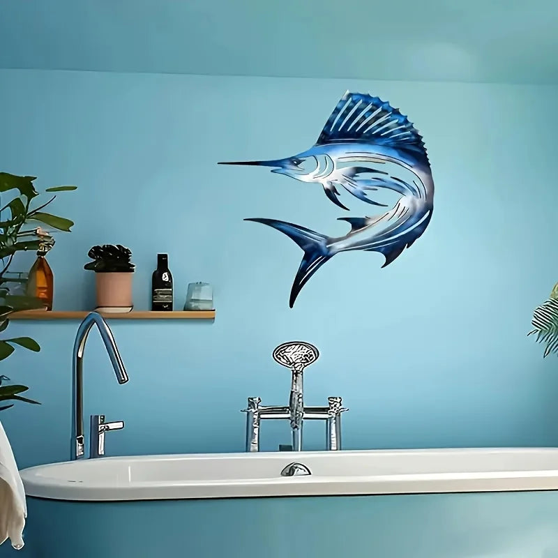 A metal fish wall art decoration featuring a blue and silver fish mounted on a light blue wall above a bathroom sink.
