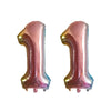 Two foil number balloons shaped like the number 1, in a metallic pink color.