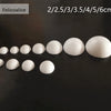 A row of white polystyrene foam balls of various sizes are displayed on a dark surface.