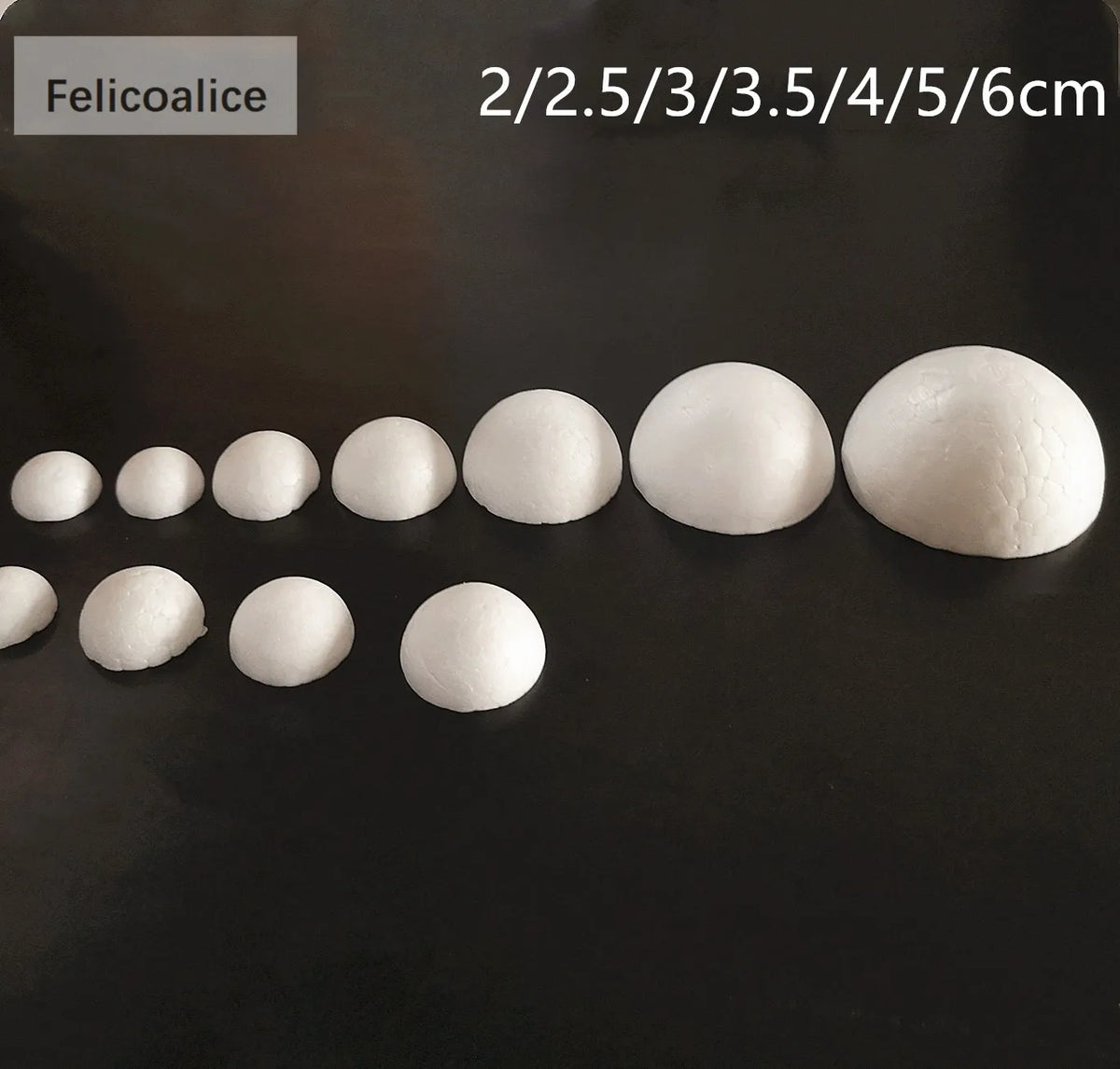 A row of white polystyrene foam balls of various sizes are displayed on a dark surface.