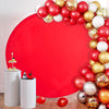 A red circular photo backdrop decorated with a garland of gold, silver, and red spherical balloons.