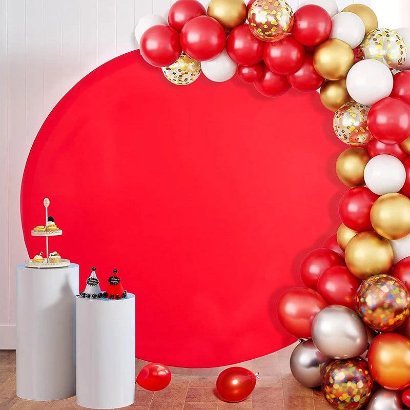 A red circular photo backdrop decorated with a garland of gold, silver, and red spherical balloons.