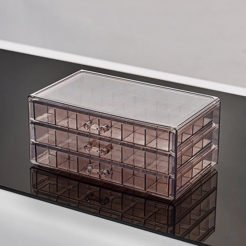 Clear acrylic jewelry organizer with three drawers shown in a reflection.