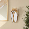 Golden cicada hanging ornament made of resin with wings mounted on a wall.