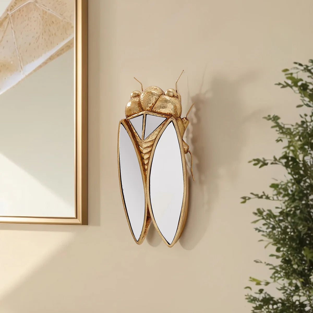 Golden cicada hanging ornament made of resin with wings mounted on a wall.