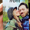 A photo of a couple kissing, featuring a woman with long hair and a man with a beard, set against a natural outdoor backgroun